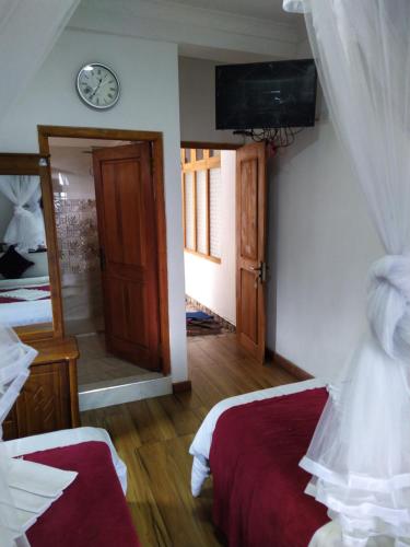 a bedroom with two beds and a clock on the wall at RIO Homestay in Haputale