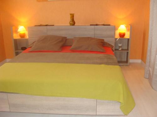 a bedroom with a large yellow bed with two lamps at Chambre d'Hôtes Chez Eliane et Bernard in Lisle-sur-Tarn