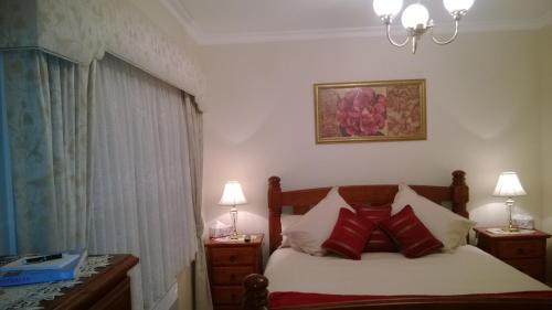 1 dormitorio con 1 cama con almohadas rojas en Cleggett Estate, en Gisborne