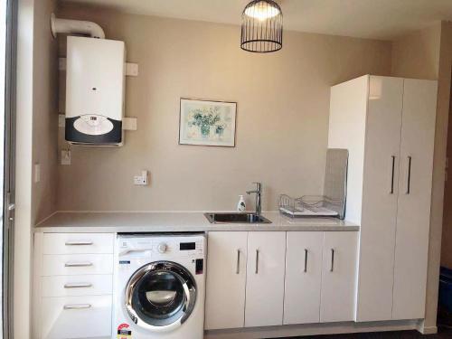 a kitchen with a washing machine and a sink at Mia Cosy Holiday Home in Rotorua