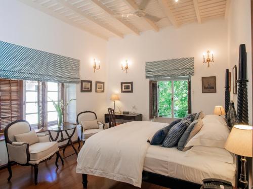 1 dormitorio con 1 cama grande con sillas y ventanas en Le Colonial 1506 - Exclusive Luxury Hideaway, en Kochi