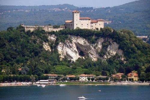 a large castle on top of a hill over water at Grandma's garden house in Angera
