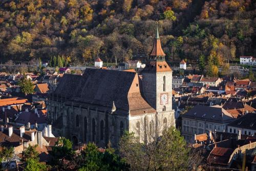 an old building with a clock tower in a city at Studio Aries Postavarului in Braşov