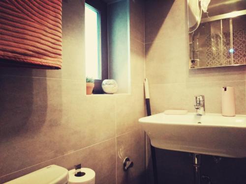 a bathroom with a sink and a toilet and a window at Quacketta in Villajoyosa