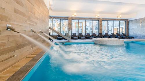 a swimming pool with chairs in a building at Michano Apartamenty Premium in Kołobrzeg