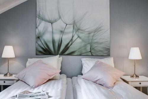 a bedroom with two beds with pink pillows and a painting at Ludvika Stadshotell in Ludvika