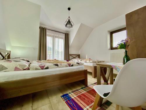 a bedroom with two beds and a table and a chair at Villa Jarka Rent in Ždiar
