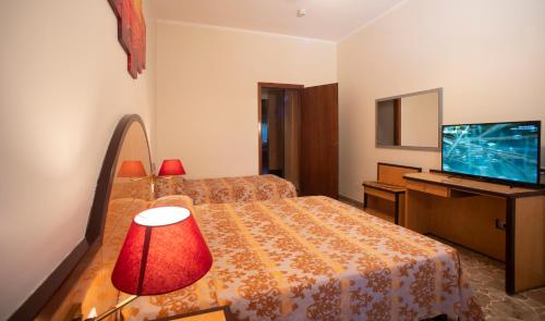 a hotel room with a bed and a desk with a television at H&L Hotel in Cinisello Balsamo