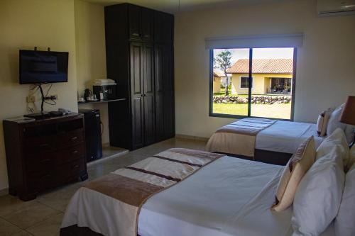 a hotel room with two beds and a television at Hacienda Los Molinos Boutique Hotel & Villas in Boquete