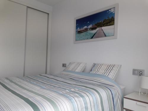 a white bedroom with a bed and a picture on the wall at Las Terrazas Golf Resort Rental in Roldán