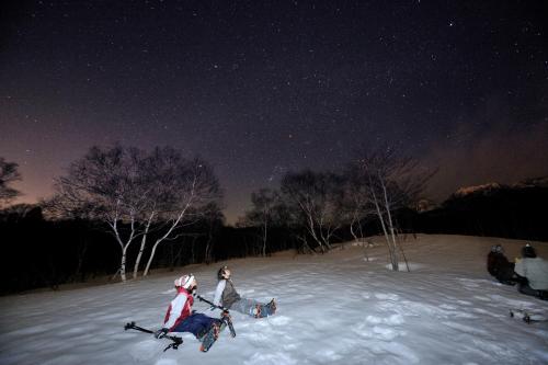 two people on skis in the snow at night at Resort Project Myoko Kogen in Myoko
