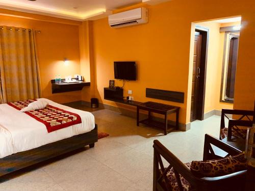 a bedroom with a bed and a desk and a tv at The Loft Hotel, Siliguri in Siliguri