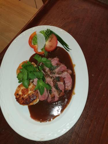 a plate of food with meat and sauce on a table at Landgasthof zum Brückenwirt in Starnberg