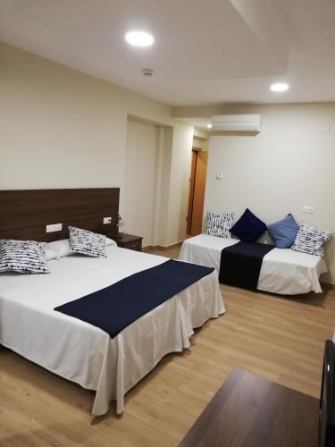 a bedroom with two beds with blue and white pillows at Hosteria de Rafi in Priego de Córdoba