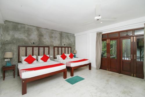 a bedroom with two beds with red pillows at Villa 45 - Balapitiya in Balapitiya