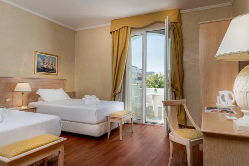 a hotel room with two beds and a balcony at Hotel De Londres in Rimini