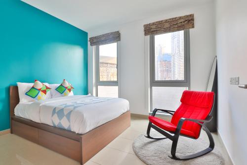 a bedroom with a bed and a red chair at OYO 398 Home Standpoint Tower A , 1 BR in Dubai