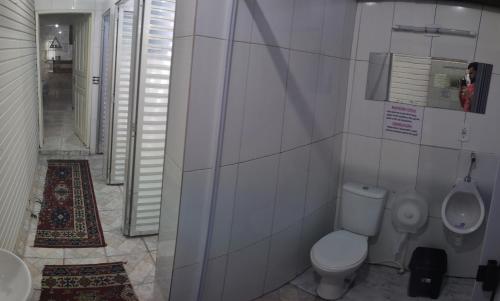 a bathroom with a toilet and a sink and a urinal at Pousada Alojaki Hostel in Praia Grande