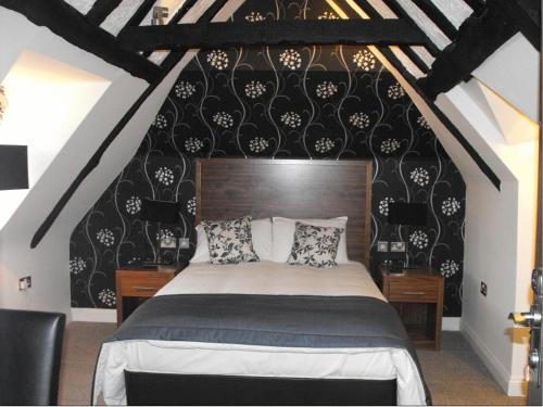 a bedroom with a bed with black and white wallpaper at The Boleyn Hotel in Staines