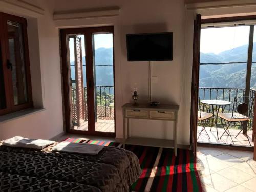 a bedroom with a bed and a balcony with a television at Sophia's Stone House in Dhimitsana