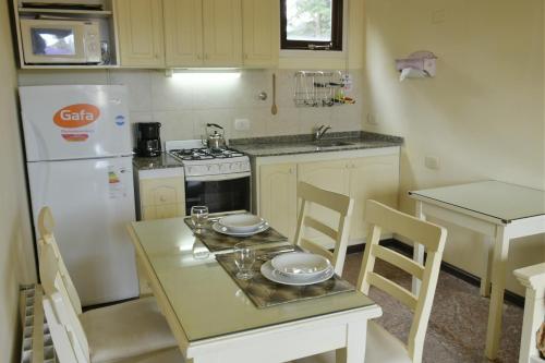 a small kitchen with a table and a white refrigerator at Apart Hotel Las Hadas Carilo in Carilo