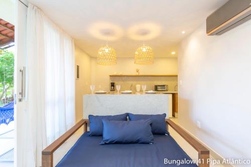 uma sala de estar com um sofá azul e uma cozinha em Pipa Atlântico Bungalow 41 em Pipa