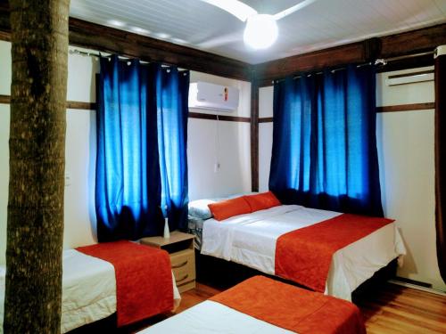 a bedroom with two beds and blue curtains at Residencial Saldanha in Gramado