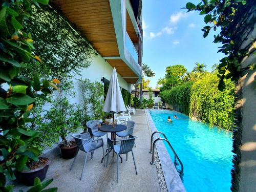 a patio with a table and chairs next to a pool at Lemonade Phuket Hotel -SHA Plus in Chalong