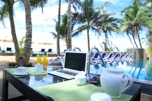 a laptop on a table next to a swimming pool at Nico Beach Hotel in Hikkaduwa