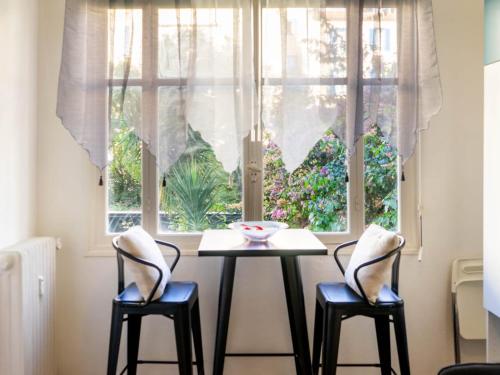 een tafel en twee stoelen voor een raam bij STUDIO PROMENADES DES ANGLAIS - CARRE&OR NICE in Nice