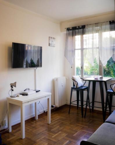 - un salon avec deux tables et une télévision murale dans l'établissement STUDIO PROMENADES DES ANGLAIS - CARRE&OR NICE, à Nice