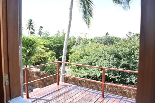a balcony with a view of a palm tree at Pousada Velho Bateau in Atins