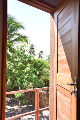 an open door to a balcony with a palm tree at Pousada Velho Bateau in Atins