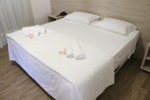 a white bed with white sheets and dolls on it at Serrano Hotel in Ribeira