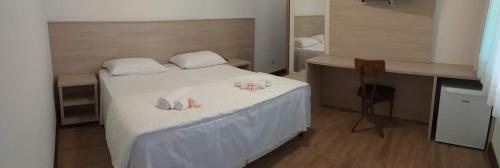 a bedroom with a bed with white sheets and two mugs at Serrano Hotel in Ribeira