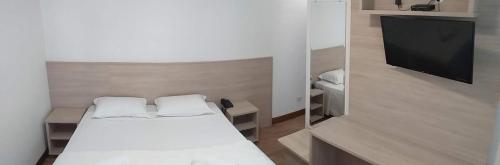 a small bedroom with a bed and a flat screen tv at Serrano Hotel in Ribeira