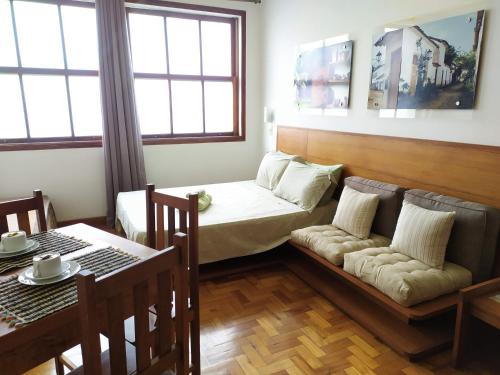 a room with a bed and a couch and a table at Flat aconchegante no Centro Histórico in São João del Rei