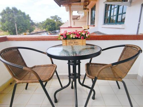 una mesa y sillas en un balcón con flores en The Maple Homestay @ Kota Laksamana Melaka, en Melaka