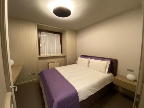 una piccola camera da letto con un letto con una coperta viola di Maison Vittorio a Cogne