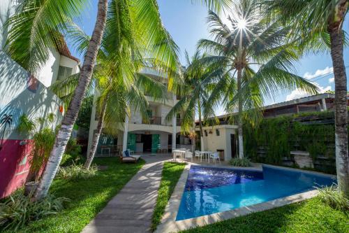 an exterior view of a villa with a swimming pool and palm trees at Pousada Unaí in Porto De Galinhas