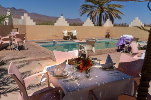 uma mesa com uma toalha de mesa azul ao lado de uma piscina em Riad Hiba em Foum Zguid