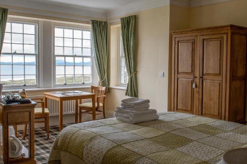 a bedroom with a bed and a table and windows at Crown Lodge in Harlech