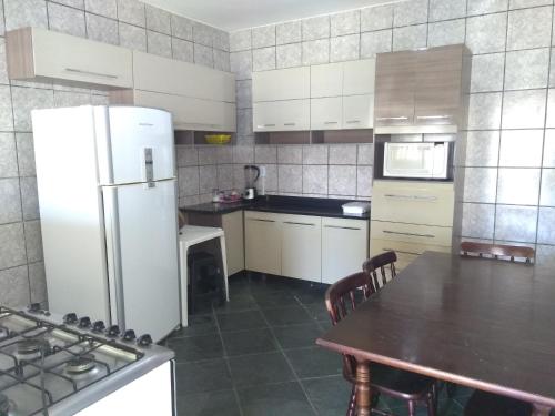 a kitchen with a white refrigerator and a table at Casa para temporada in Ilha Comprida