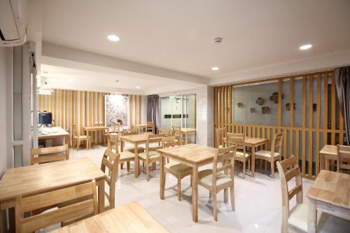 Super OYO 483 Pannee Hotel Khaosan في بانكوك: مطعم بطاولات خشبية وكراسي خشبية