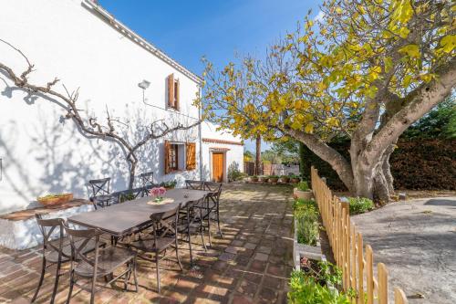 a patio with a table and chairs and a tree at Masia Can Magan Lux, Ideal Grupos 20pax in Palafolls