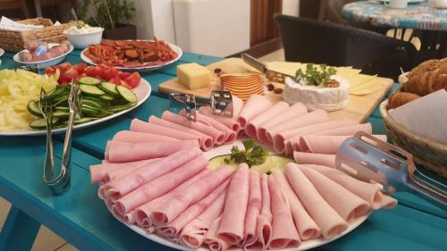 a table topped with plates of meat and cheese at Balaton Colors Beach Hotel in Siófok