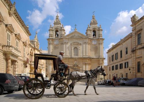 a man in a horse drawn carriage in front of a building at Central Rooms - Near Valletta & Sliema - Best Bus Lines in Hamrun