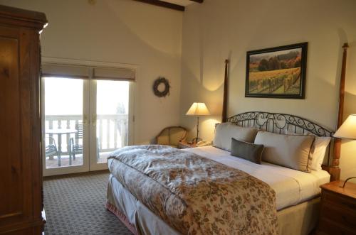 a hotel room with a bed and a balcony at Vineyard Country Inn in St. Helena