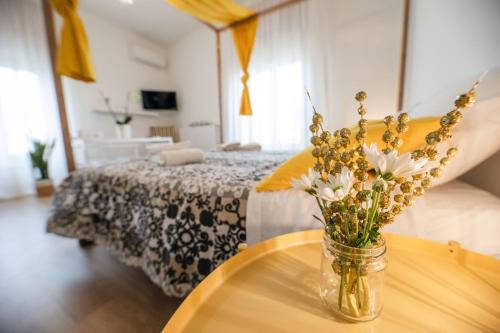 a vase of flowers on a table next to a bed at Le Stanze Di Brando E Nico in Tricase