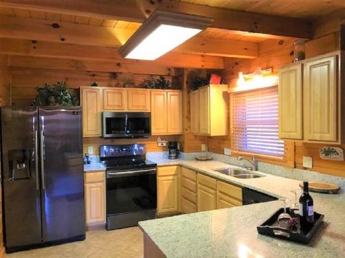 cocina con nevera de acero inoxidable y fregadero en Knotty By Nature, en Gatlinburg